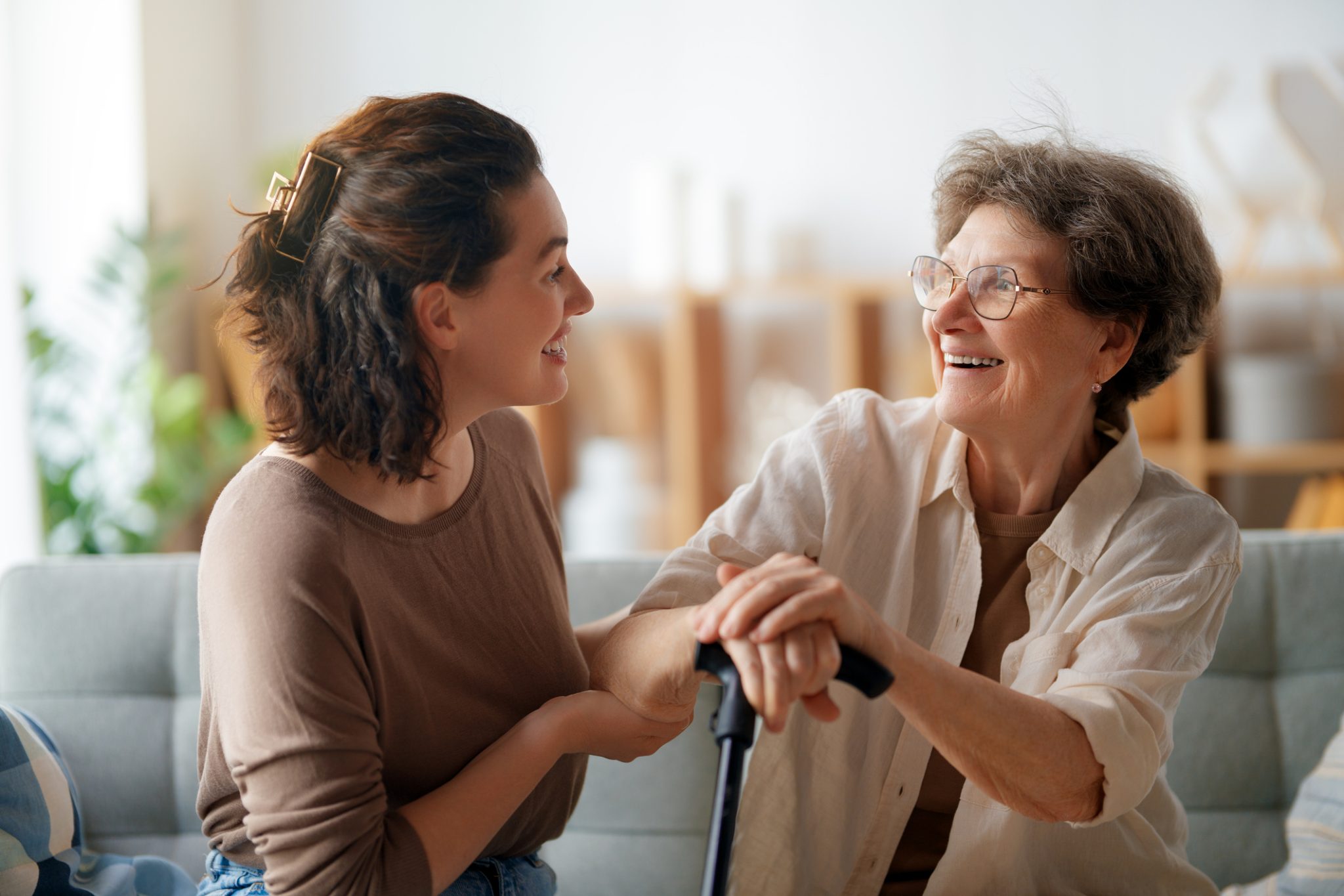 A female caregiver assists an older adult with daily tasks at home during early home care planning.